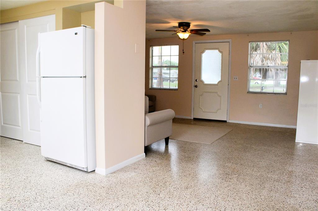 A kitchen area with a white refrigerator opens into a living room with tile flooring — 4619 IRENE LOOP, NEW PORT RICHEY, FL