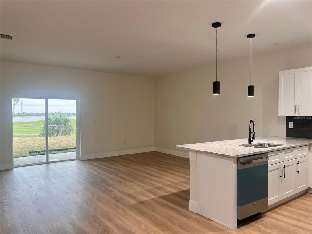 A kitchen island with a sink and pendant lights overlooks an open living area — 7214-7216 DAVID BOULEVARD, PORT CHARLOTTE, FL