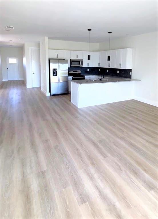 A kitchen with white cabinets, stainless steel appliances, and a peninsula island in an open room — 7214-7216 DAVID BOULEVARD, PORT CHARLOTTE, FL