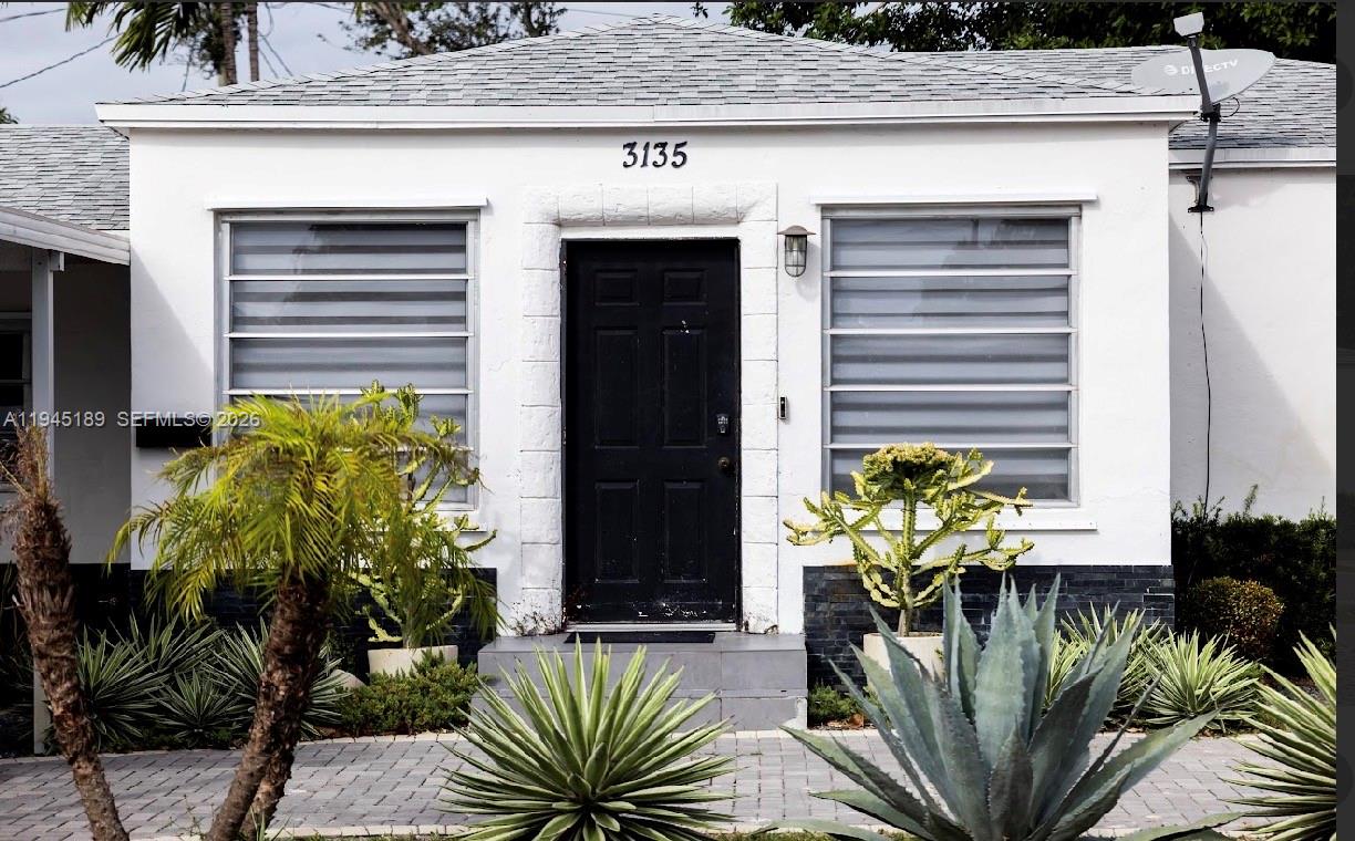 A white house exterior features a black front door, two windows, and desert landscaping — 3135 NW 18th St, Miami FL 33125, MIAMI, FL