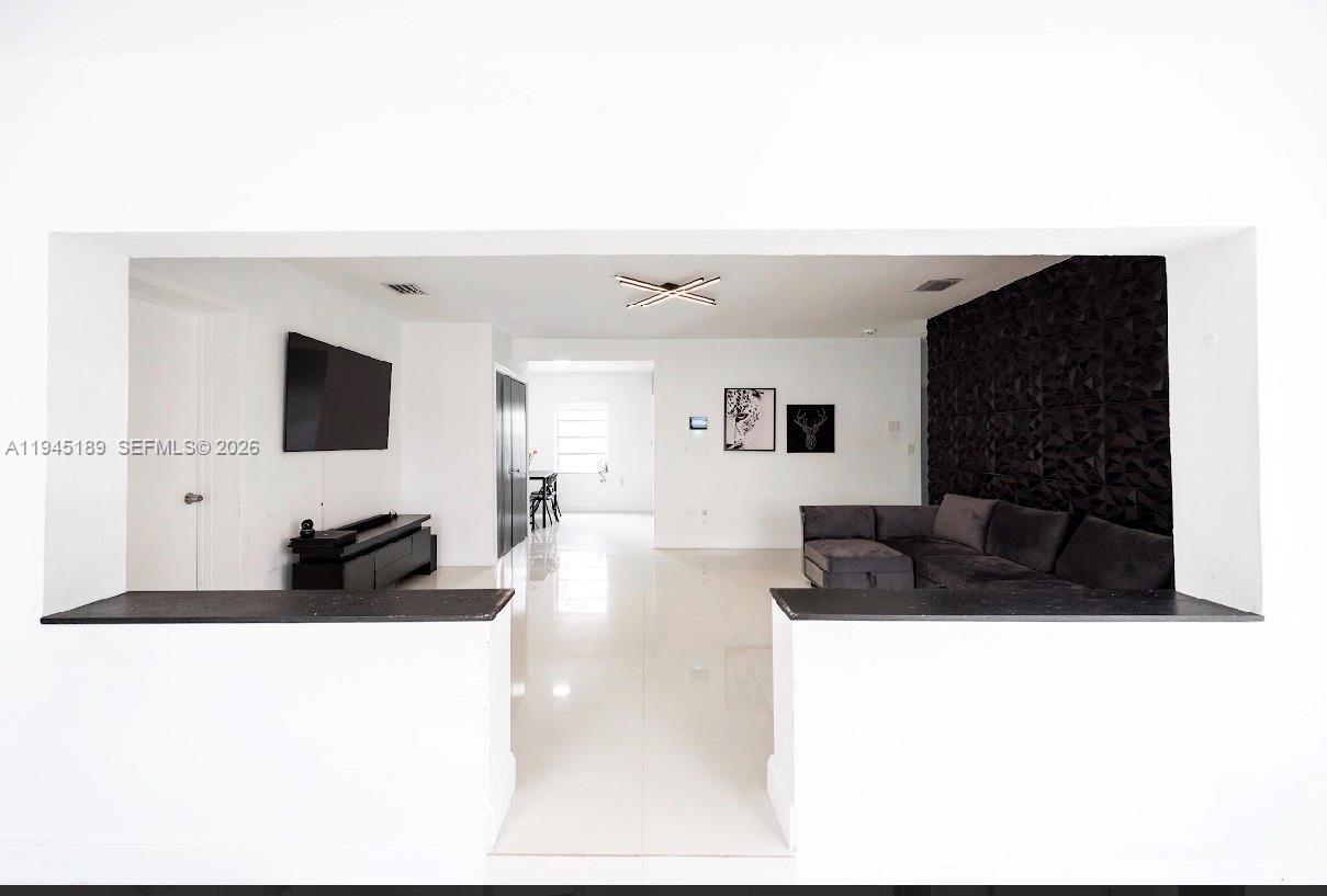A living room features white walls, tile floors, a dark accent wall, and a sectional sofa — 3135 NW 18th St, Miami FL 33125, MIAMI, FL
