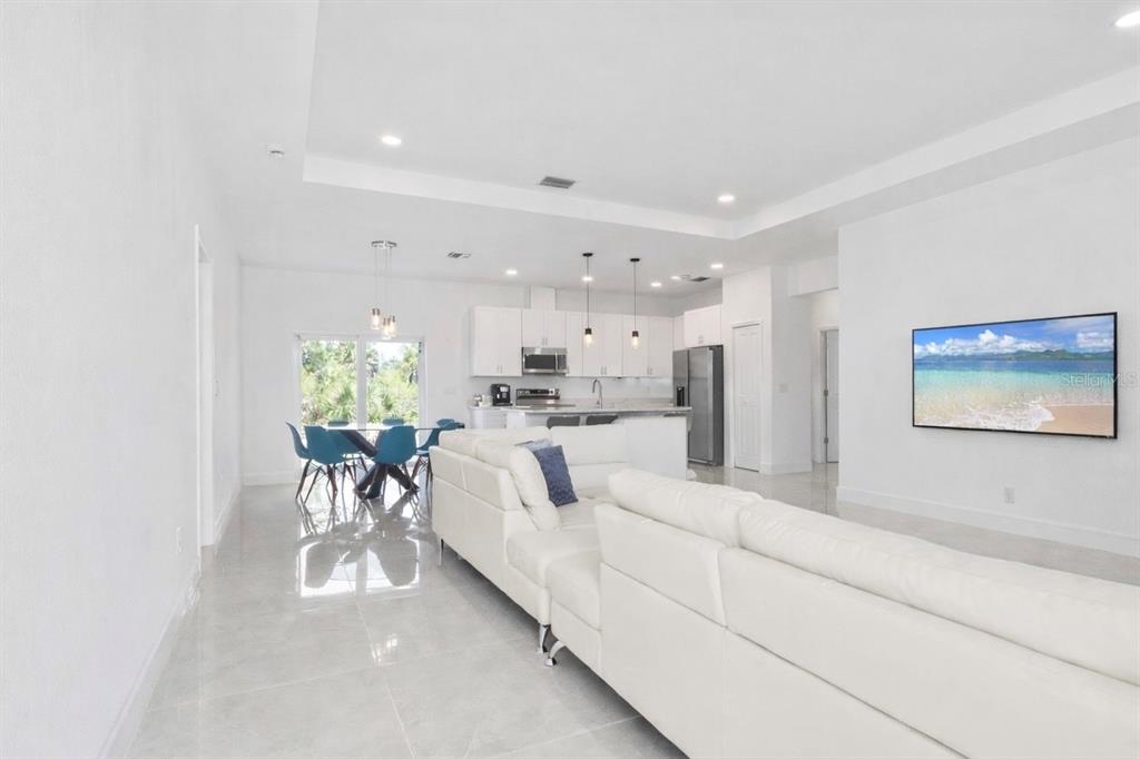 An open-concept living room and kitchen featuring white cabinetry, tile floors, and a sectional sofa — 15473 LAKELAND CIRCLE, PORT CHARLOTTE, FL