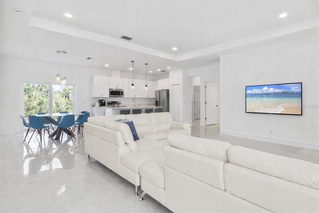 An open-concept living room and kitchen featuring white cabinetry, tile floors, and a sectional sofa — 15473 LAKELAND CIRCLE, PORT CHARLOTTE, FL