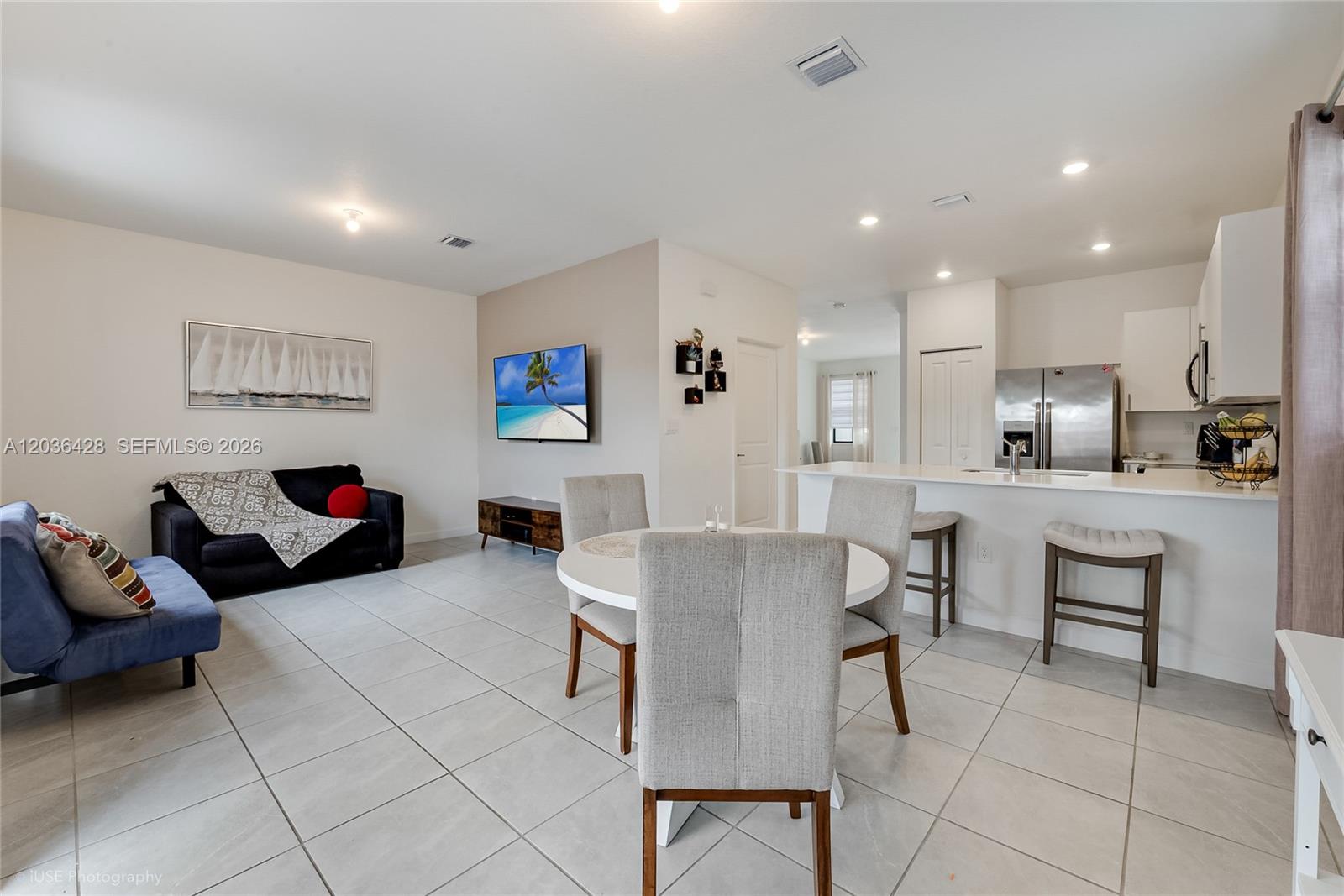 An open-concept living and dining area features tile flooring, white cabinetry, and a kitchen island — 23105 SW 128th Pl, Miami FL 33170, MIAMI, FL