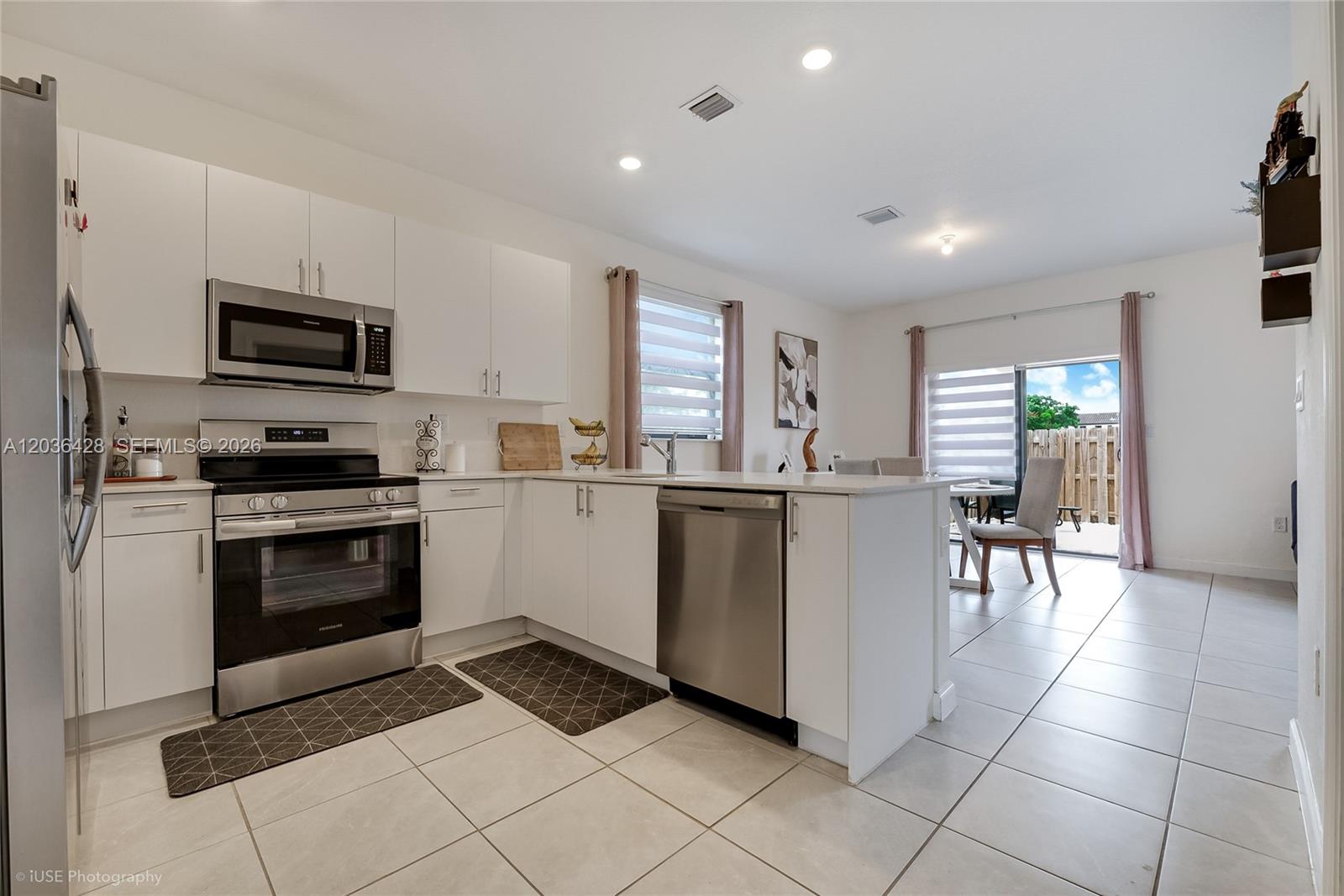 A modern kitchen features white cabinets, stainless steel appliances, and tile flooring — 23105 SW 128th Pl, Miami FL 33170, MIAMI, FL