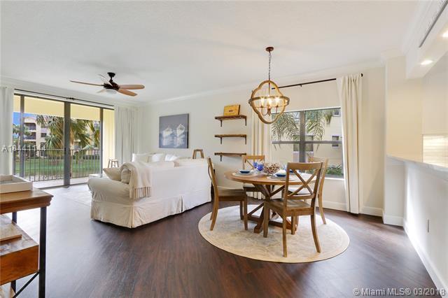 A living and dining area features dark wood floors, a white sofa, and a round table — 100 Uno Lago Drive # 205, Juno Beach FL 33408, JUNO BEACH, FL
