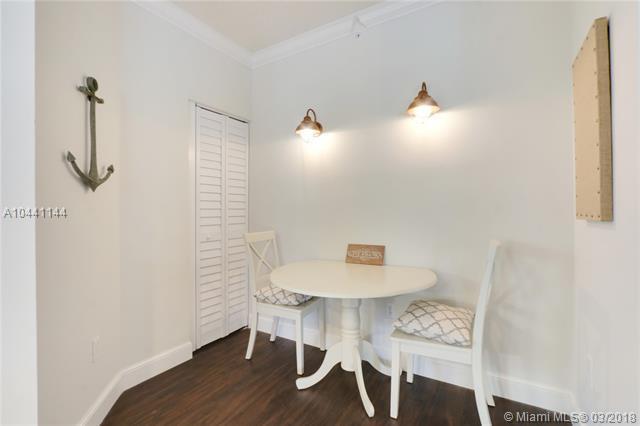 A small dining area features a round white table, two chairs, and wall-mounted light fixtures — 100 Uno Lago Drive # 205, Juno Beach FL 33408, JUNO BEACH, FL