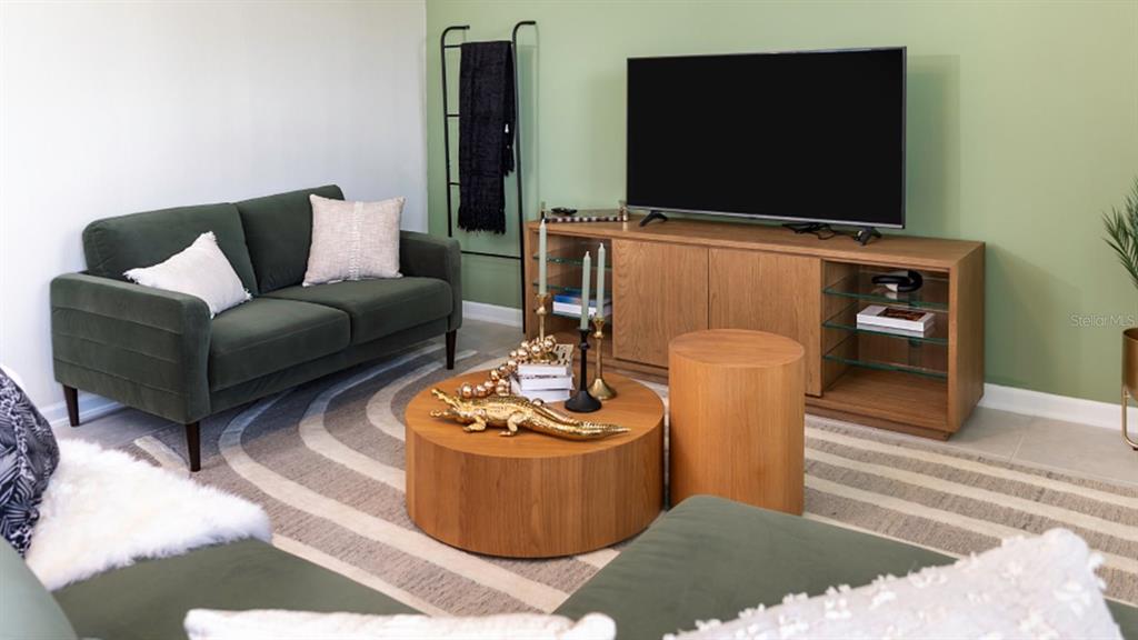 A living room features a green sofa, a round wooden coffee table, and a television console — 5844 ENERGY WAY, CLERMONT, FL