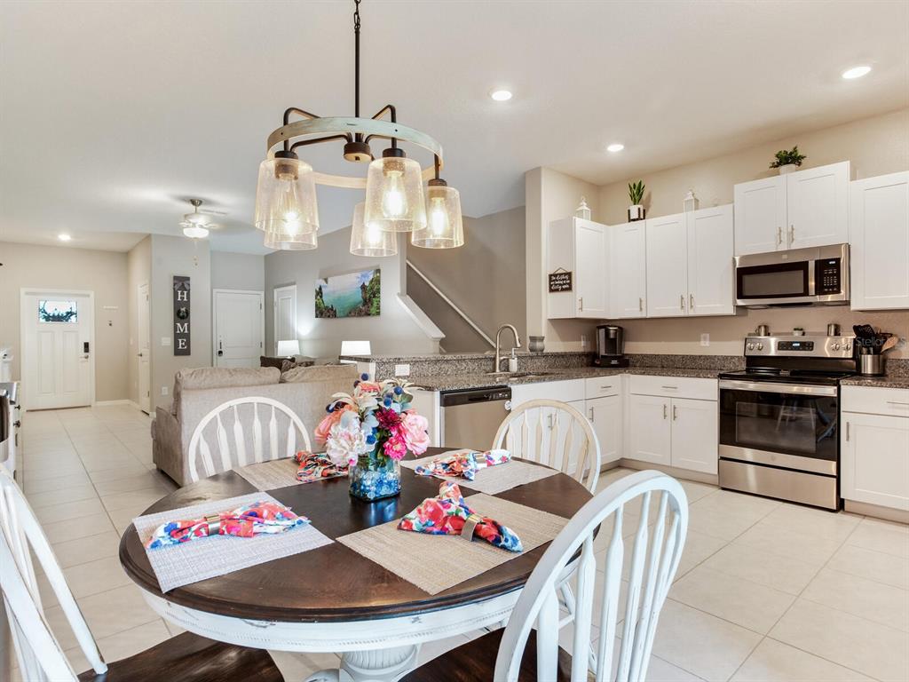 A dining area with a round table sits in front of a white-cabinet kitchen — 2561 CHARLAN COURT, HOLIDAY, FL