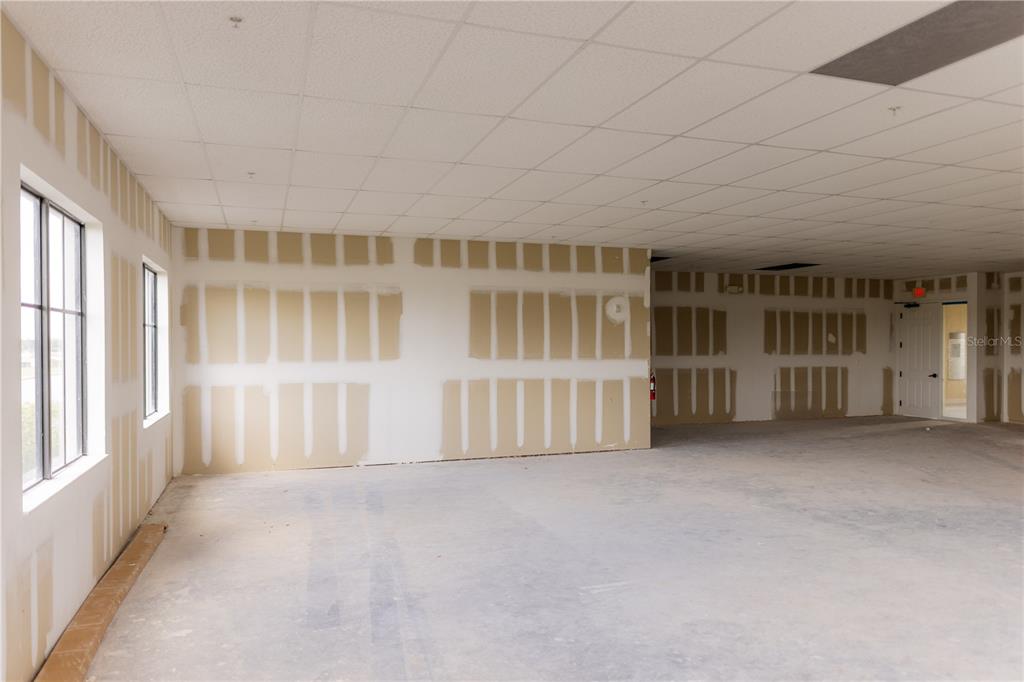 An unfinished commercial interior features drywall with exposed seams, a drop ceiling, and large windows — 5920 PAN AMERICAN BOULEVARD UNIT 310, NORTH PORT, FL