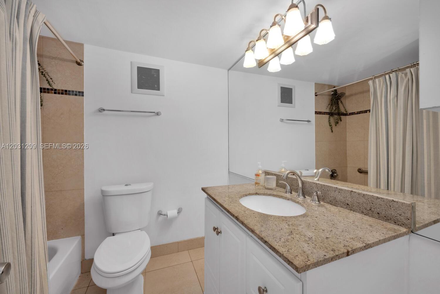 A bathroom features a granite vanity, a white toilet, and a shower with a curtain — 2539 S Bayshore Dr, Coconut Grove FL 33133, COCONUT GROVE, FL