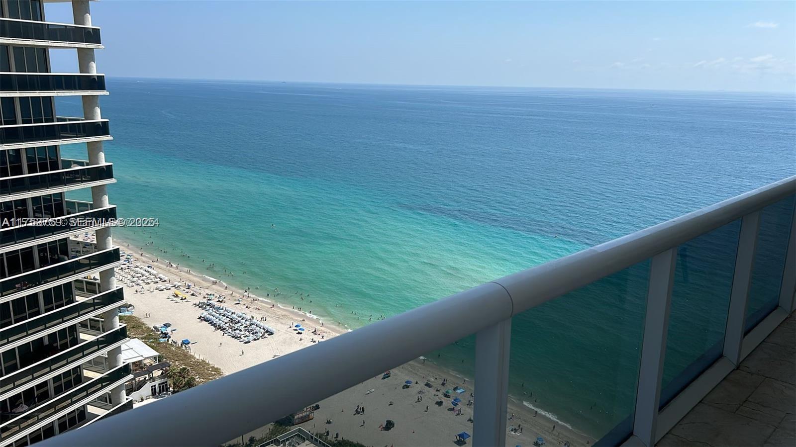 A high-angle view from a balcony overlooking a sandy beach and the ocean — 1830 S Ocean Dr # 3208, Hallandale Beach FL 33009, HALLANDALE BEACH, FL