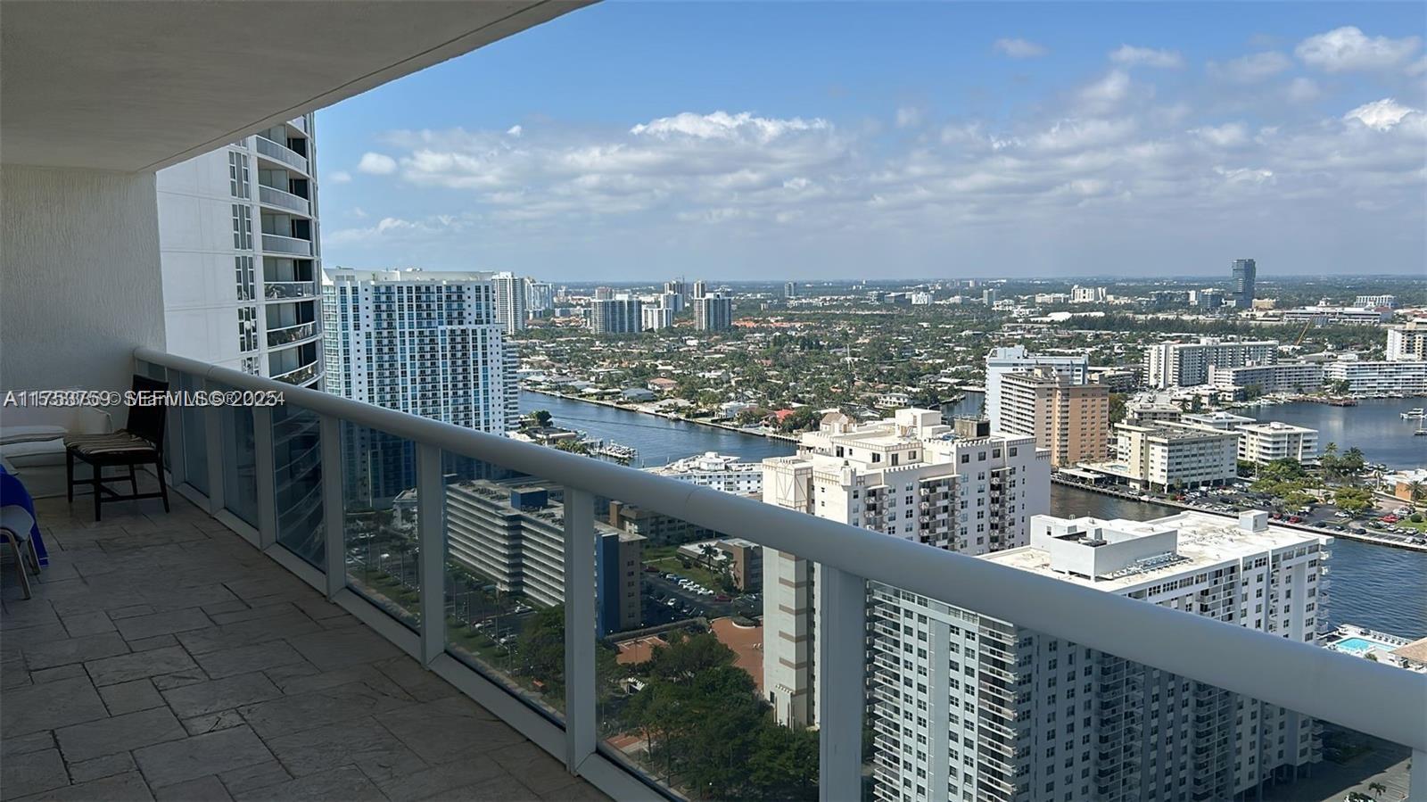 A high-rise balcony overlooks a city skyline, a waterway, and numerous residential apartment buildings — 1830 S Ocean Dr # 3208, Hallandale Beach FL 33009, HALLANDALE BEACH, FL