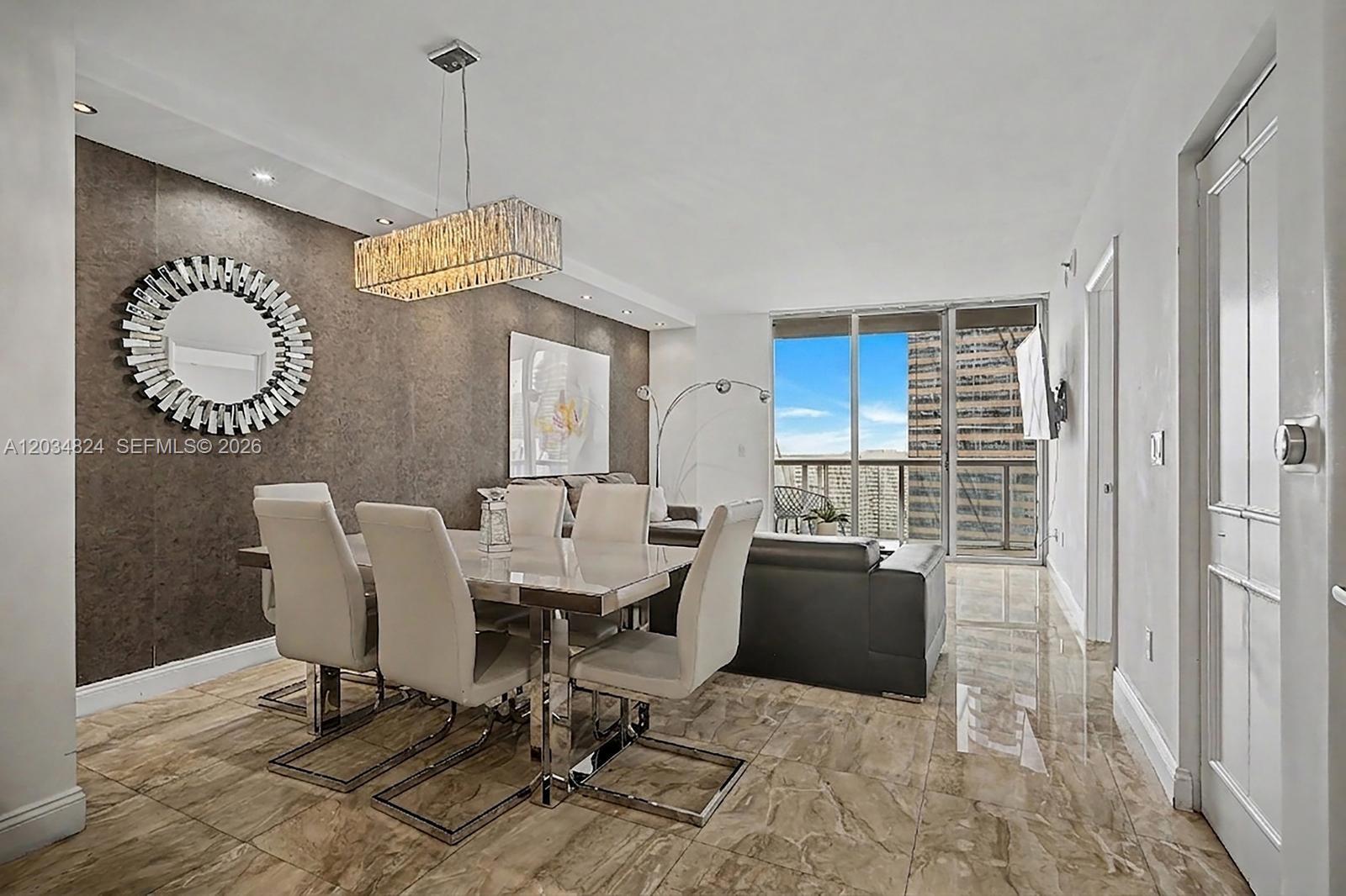 A dining and living area features a textured accent wall, modern chandelier, and marble flooring — 485 Brickell Ave # 2009, Miami FL 33131, MIAMI, FL