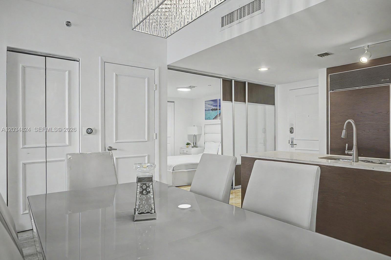 A dining area with a glass table and chairs overlooks a kitchen and bedroom — 485 Brickell Ave # 2009, Miami FL 33131, MIAMI, FL