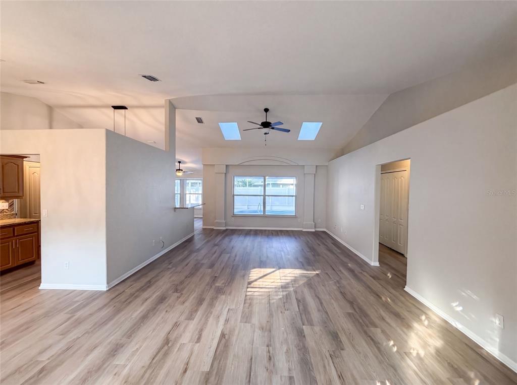 A spacious living area features vaulted ceilings, skylights, a ceiling fan, and wood-look flooring — 431 HARBOUR LIGHTS DRIVE, ORMOND BEACH, FL