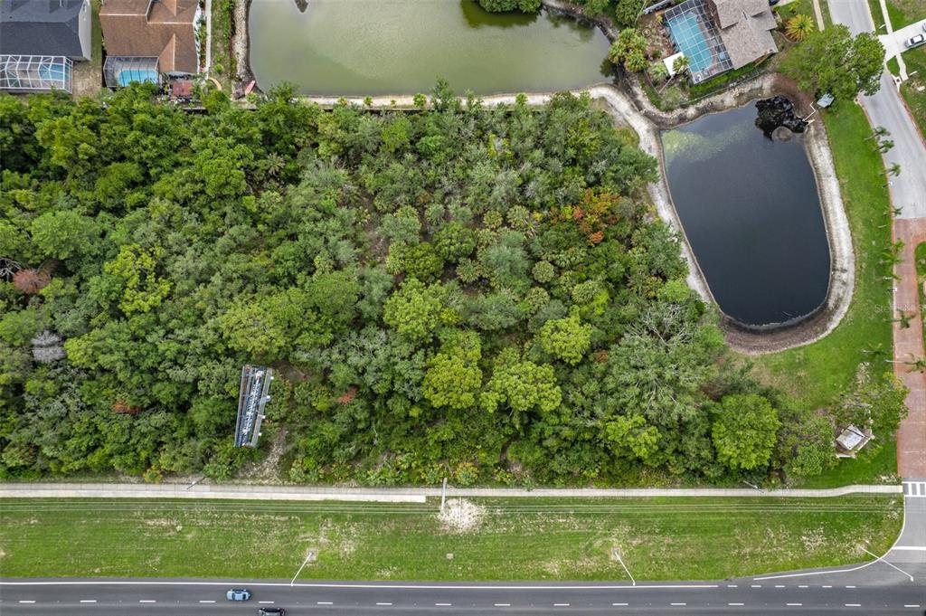 An aerial view shows a wooded vacant lot situated between a road and two ponds — 00 US HWY 19, HUDSON, FL
