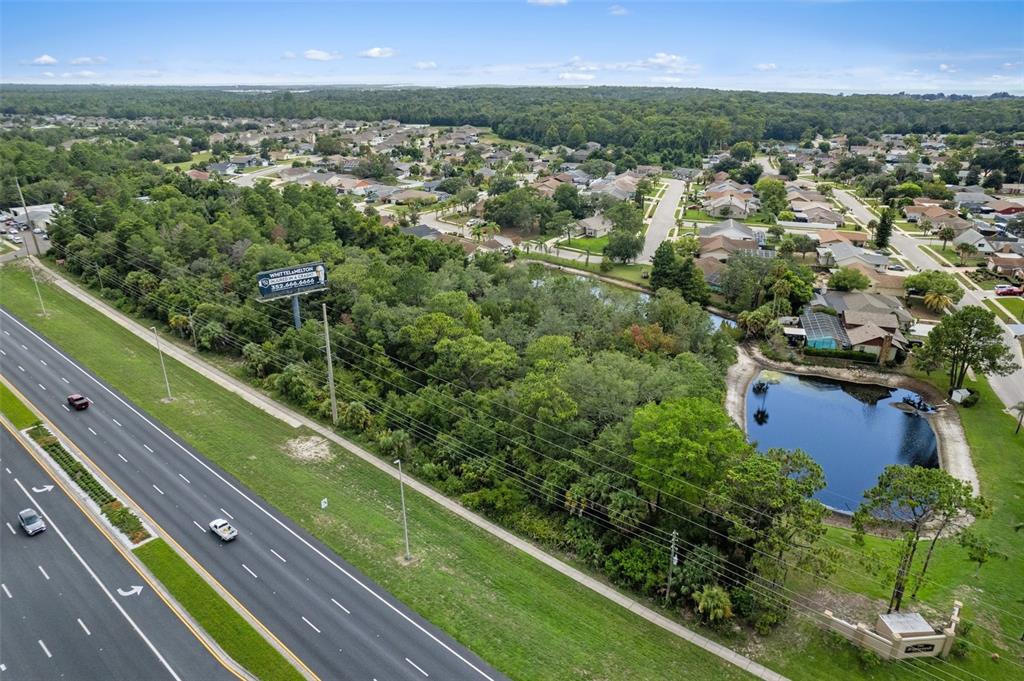 An aerial view shows a wooded lot situated between a highway and a residential neighborhood — 00 US HWY 19, HUDSON, FL