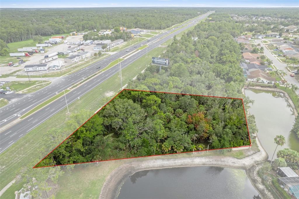 An aerial view shows a wooded, triangular-shaped plot of land adjacent to a highway — 00 US HWY 19, HUDSON, FL