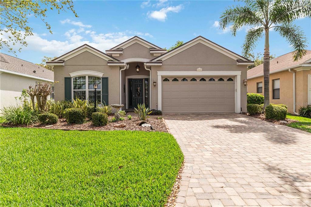 A single-story house with a beige stucco exterior, a two-car garage, and a paved driveway — 8150 INDIGO RIDGE TERRACE, UNIVERSITY PARK, FL