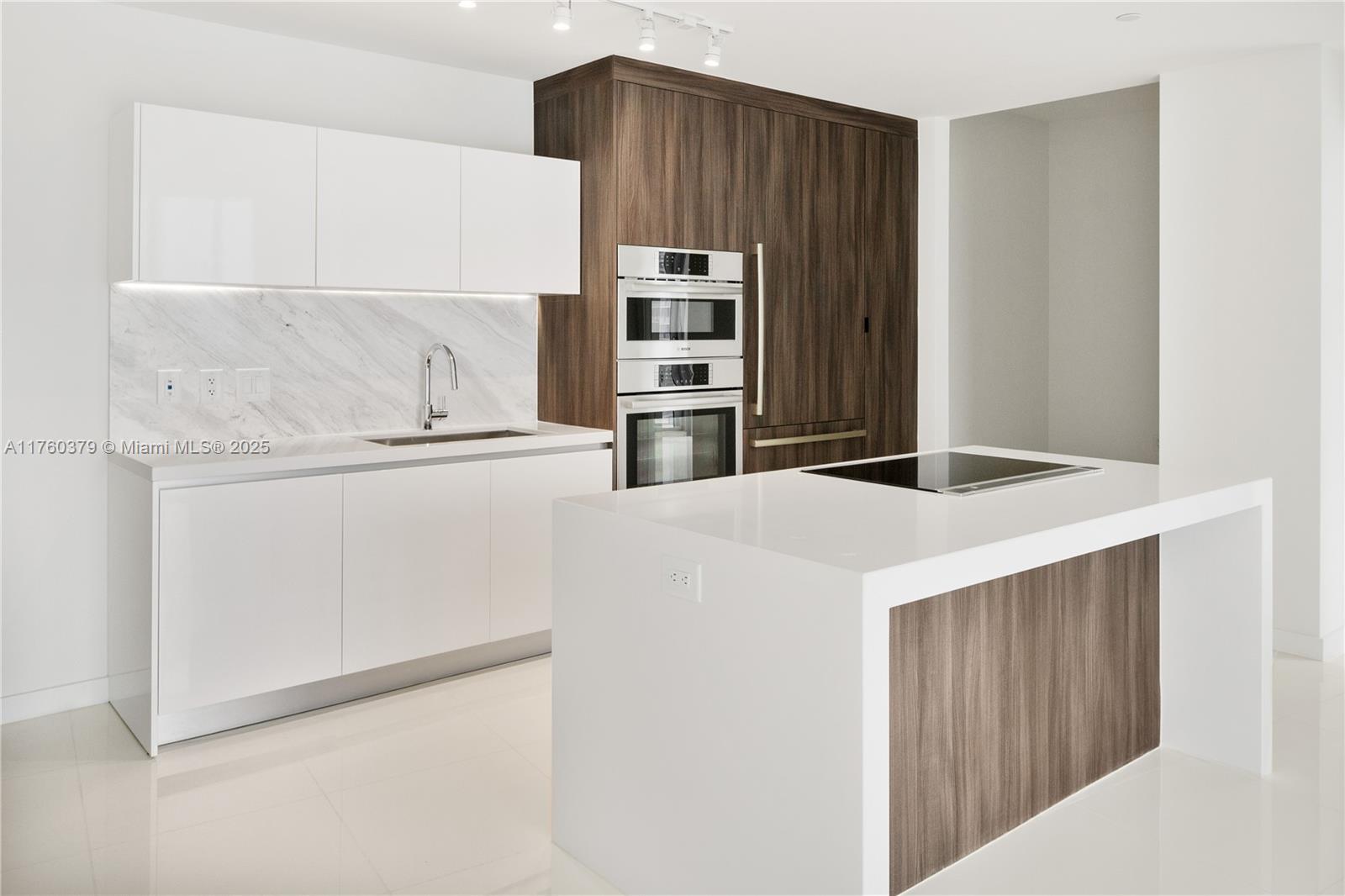 A modern kitchen features white cabinetry, a marble backsplash, wood-paneled accents, and a central island — 851 NE 1st Ave # 4203, Miami FL 33132, MIAMI, FL