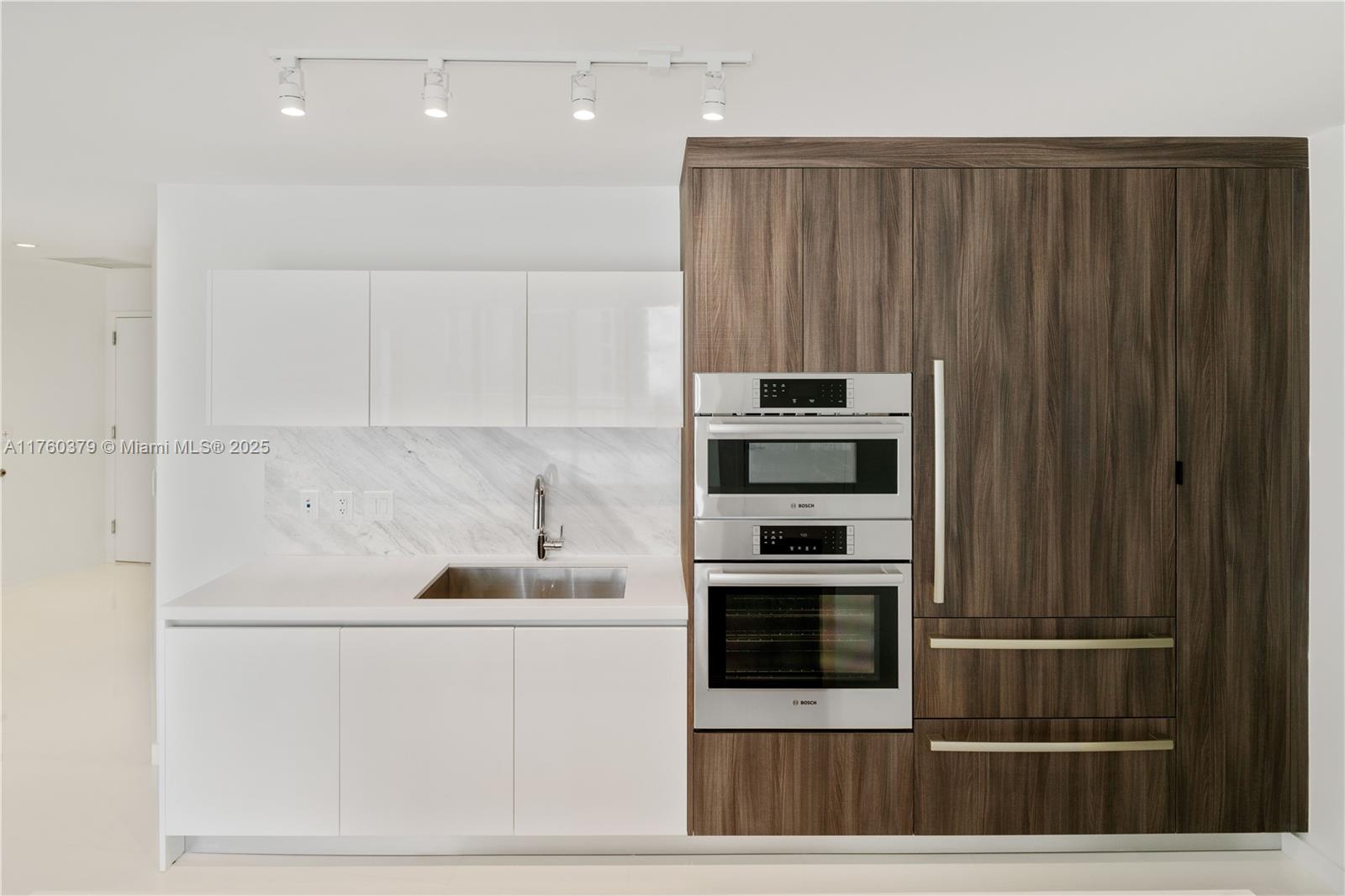A modern kitchen features white cabinets, a marble backsplash, and a wood-paneled appliance wall — 851 NE 1st Ave # 4203, Miami FL 33132, MIAMI, FL