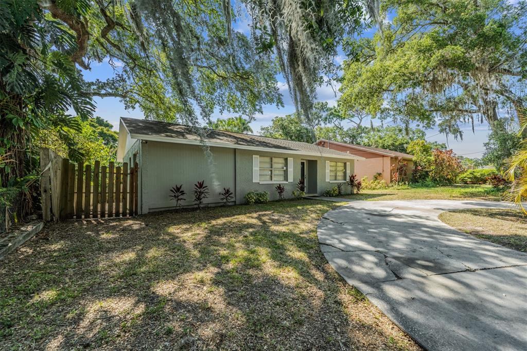 A single-story house with a gray exterior, a curved concrete driveway, and large oak trees — 9616 N OKLAWAHA AVENUE UNIT 1/2, TAMPA, FL