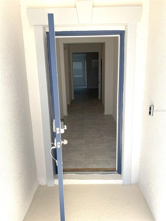 An open blue front door reveals a tiled entryway leading into a hallway — 1374 BRENTWOOD DRIVE, KISSIMMEE, FL