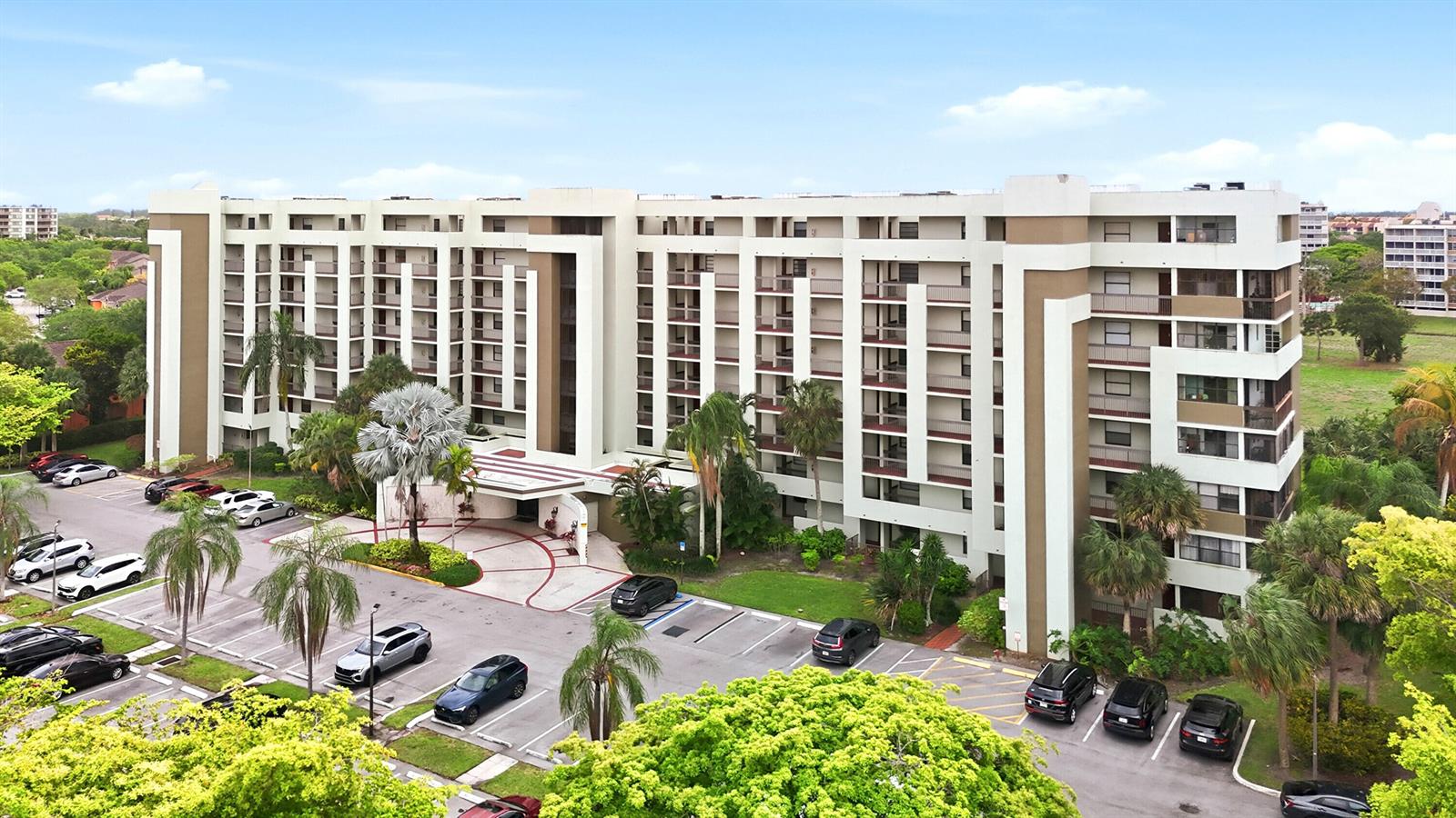 An aerial view shows a multi-story apartment building with a parking lot and landscaping — 7050 NW 44th Street # 705, Lauderhill FL 33319, LAUDERHILL, FL