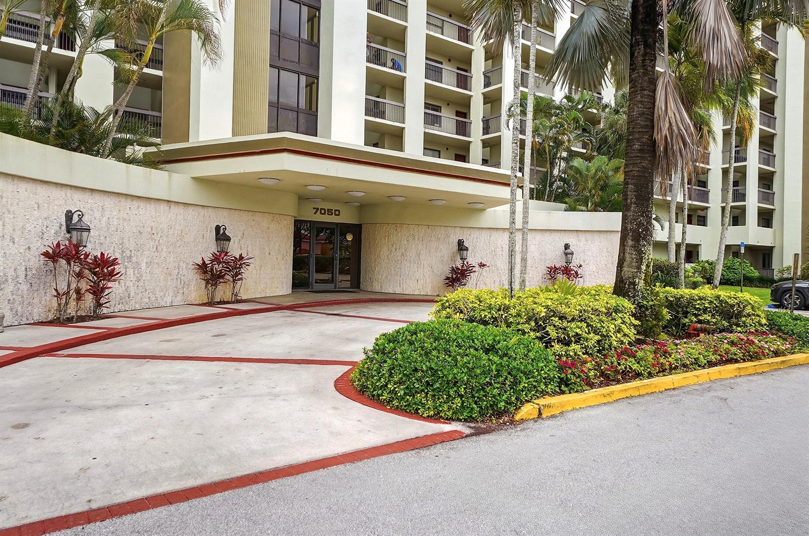 The exterior of a multi-story apartment building features a covered entrance with the number 7050 — 7050 NW 44th Street # 705, Lauderhill FL 33319, LAUDERHILL, FL