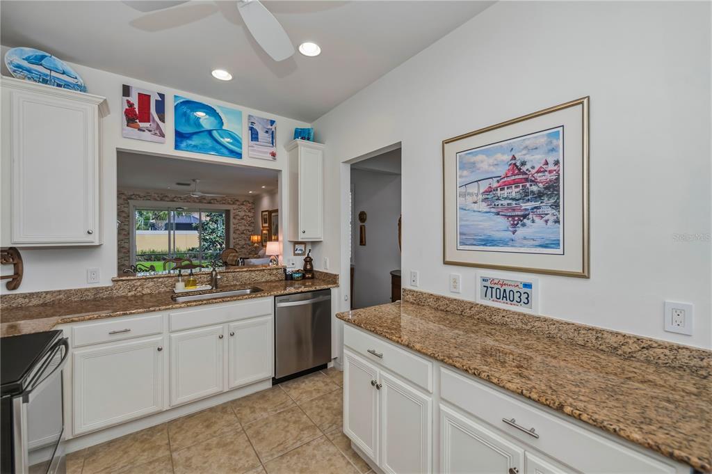 A kitchen features white cabinets, granite countertops, stainless steel appliances, and decorative wall art — 19060 LAPPACIO STREET, VENICE, FL
