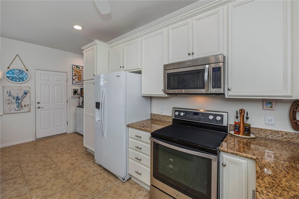 A kitchen features white cabinets, stainless steel appliances, granite countertops, and tile flooring — 19060 LAPPACIO STREET, VENICE, FL