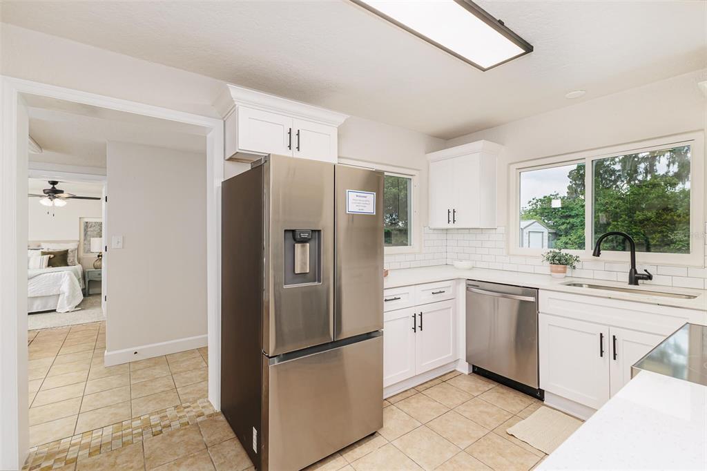 A kitchen features white cabinets, stainless steel appliances, a subway tile backsplash, and tile flooring — 1470 CAROLINA AVENUE, MULBERRY, FL
