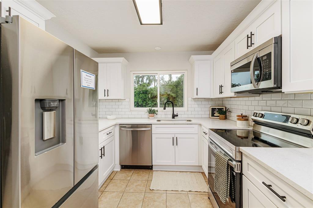 A kitchen with white cabinets, stainless steel appliances, a subway tile backsplash, and tile flooring — 1470 CAROLINA AVENUE, MULBERRY, FL