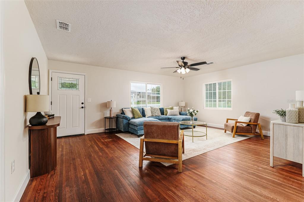 A living room features hardwood floors, a blue sectional sofa, two armchairs, and a front door — 1470 CAROLINA AVENUE, MULBERRY, FL