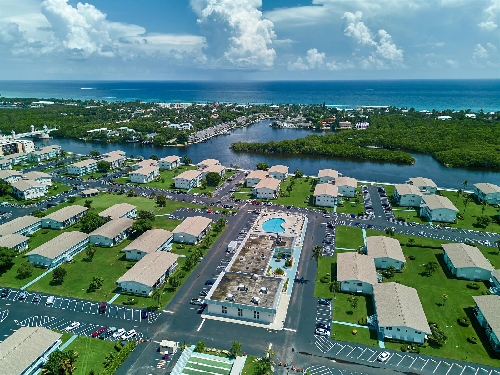 Aerial view of a residential complex with multiple buildings, a swimming pool, and surrounding greenery — 880 Horizons W # 102, Boynton Beach FL 33435, BOYNTON BEACH, FL