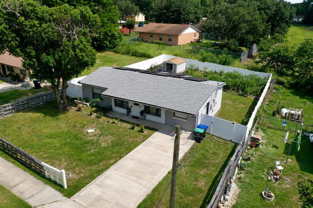 An aerial view shows a single-story house with a solar-paneled roof and a fenced backyard — 414 W ELLA J GILMORE STREET, APOPKA, FL