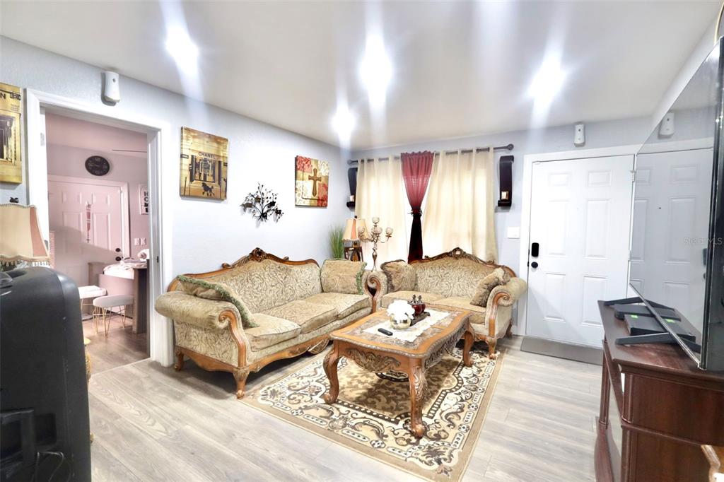 A living room features two ornate sofas, a coffee table, and a patterned area rug — 414 W ELLA J GILMORE STREET, APOPKA, FL