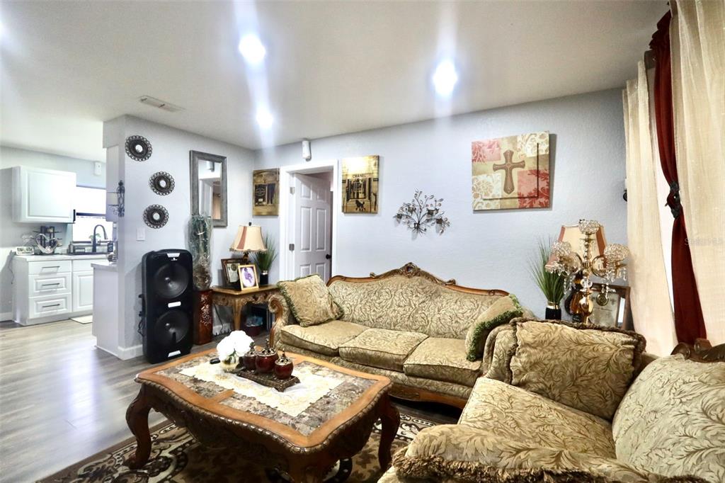 A living room features ornate patterned sofas, a marble-topped coffee table, and light-colored walls — 414 W ELLA J GILMORE STREET, APOPKA, FL