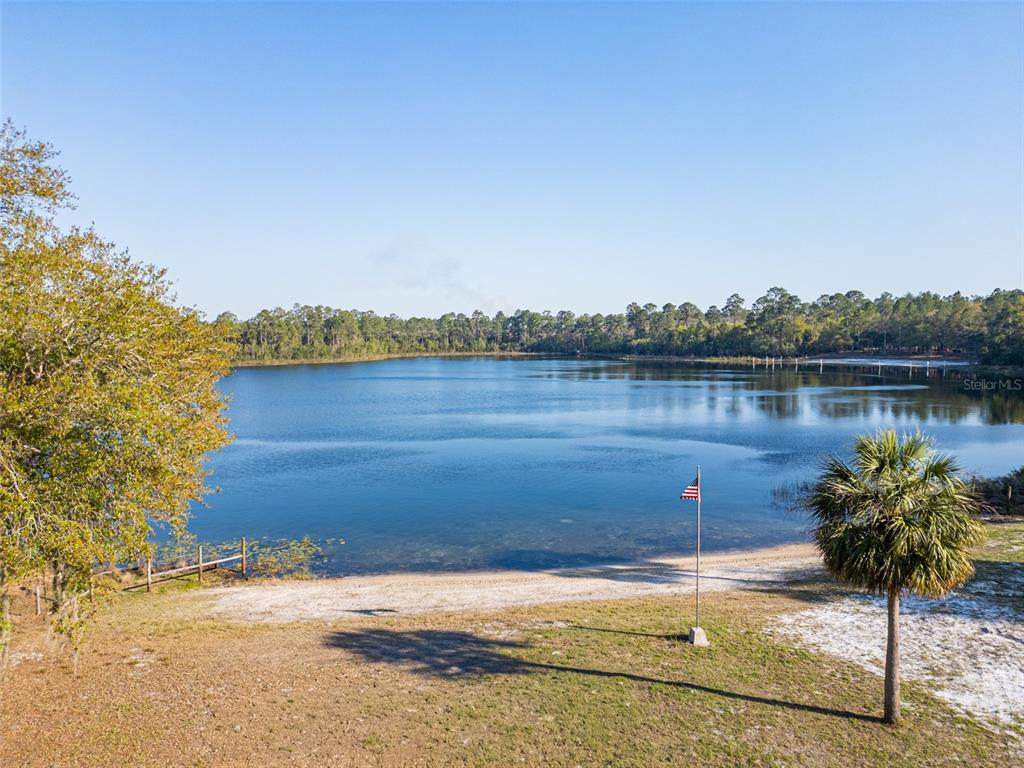 A sandy beach area borders a large lake surrounded by trees under a clear sky — 8600 NE 147TH AVENUE ROAD, SILVER SPRINGS, FL