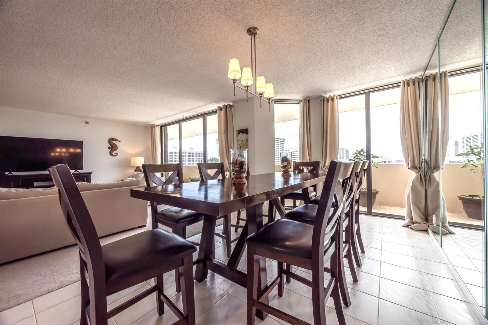 A dining area with a dark wood table and chairs sits beside a bright living room — 1401 S Ocean Boulevard # 5030, Boca Raton FL 33432, BOCA RATON, FL