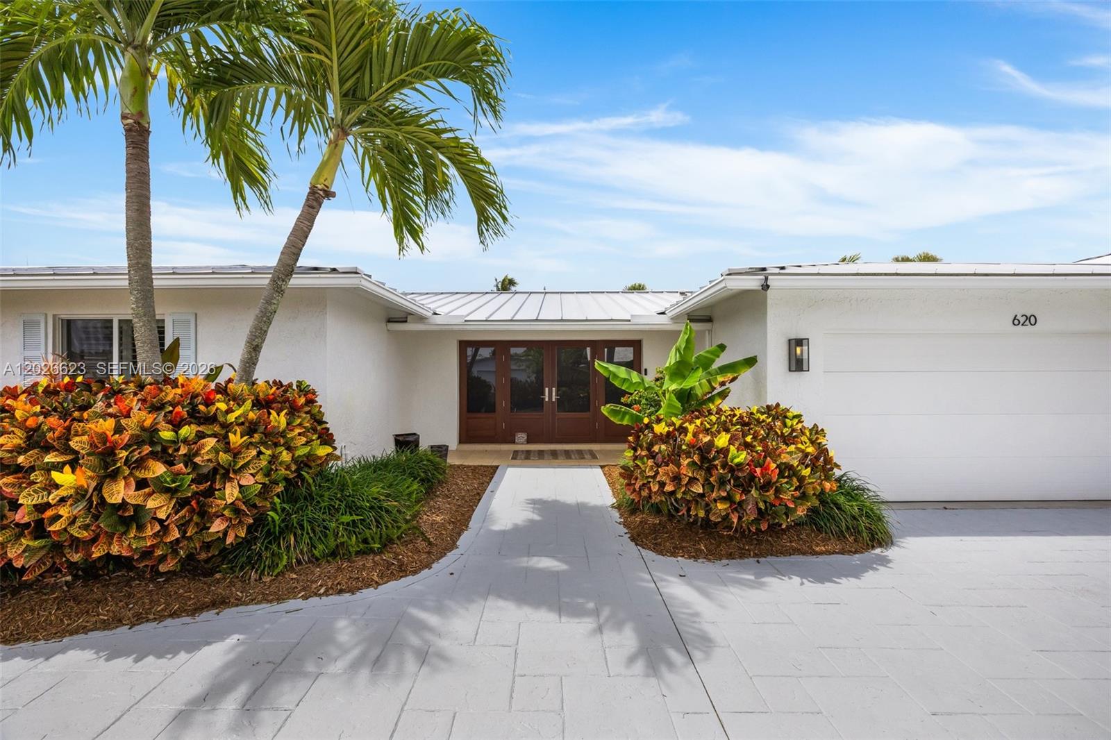 A white house exterior features a paved walkway leading to a brown double front door — 620 SE 11th St, Pompano Beach FL 33060, POMPANO BEACH, FL