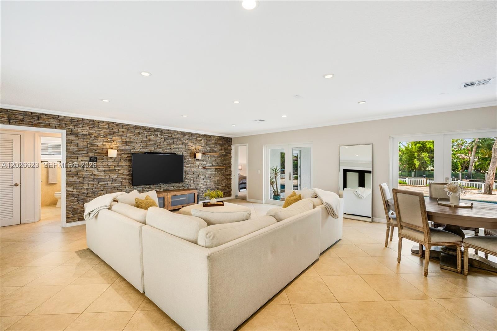 A living room features a stone accent wall, a large sectional sofa, and dining area — 620 SE 11th St, Pompano Beach FL 33060, POMPANO BEACH, FL