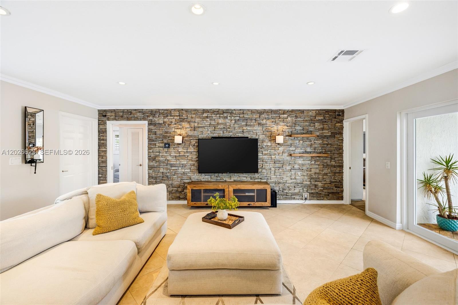A living room features a stone accent wall, a television, and a large sectional sofa — 620 SE 11th St, Pompano Beach FL 33060, POMPANO BEACH, FL