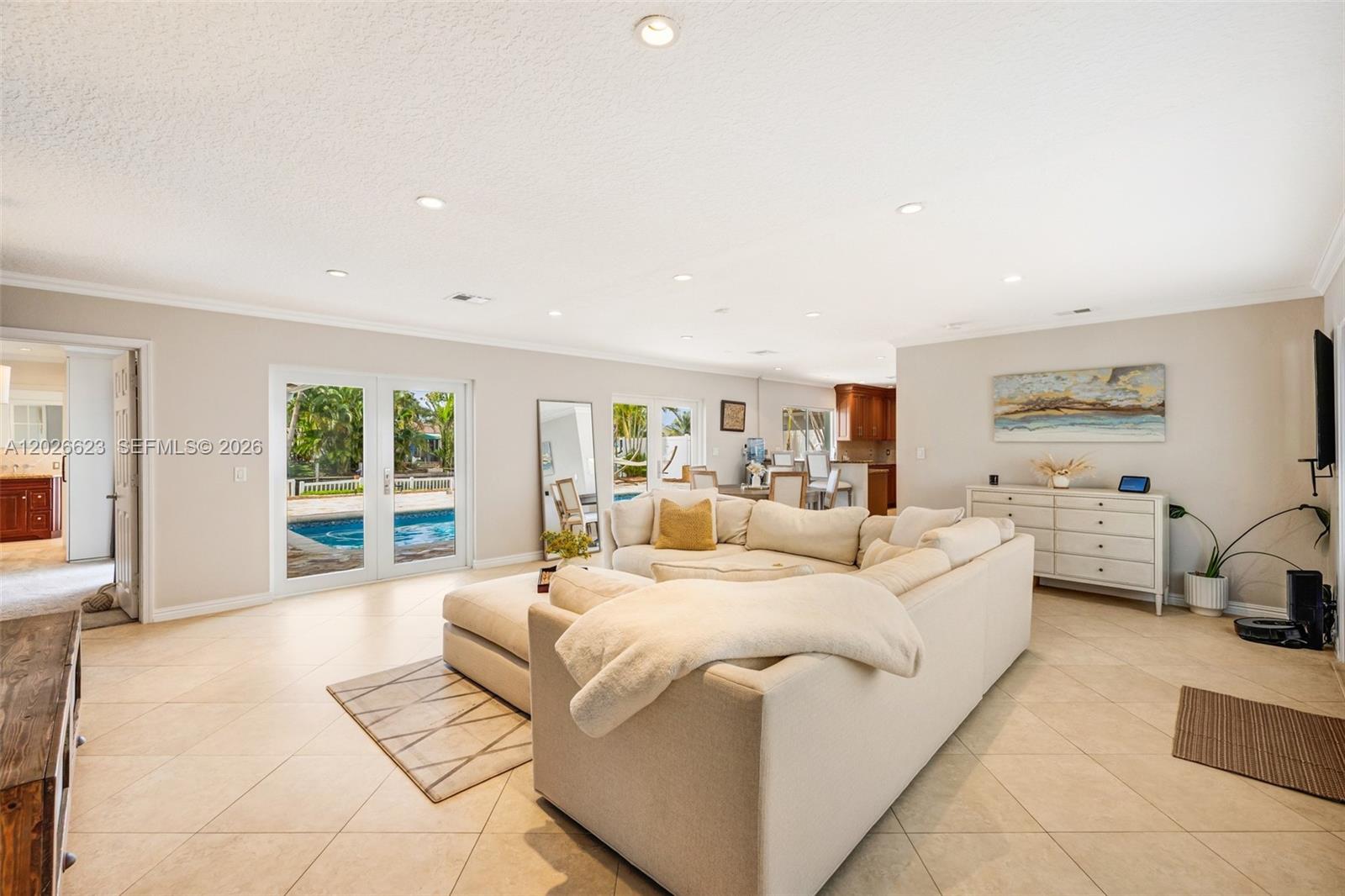 A spacious living room features a large sectional sofa, tile flooring, and glass doors to a pool — 620 SE 11th St, Pompano Beach FL 33060, POMPANO BEACH, FL