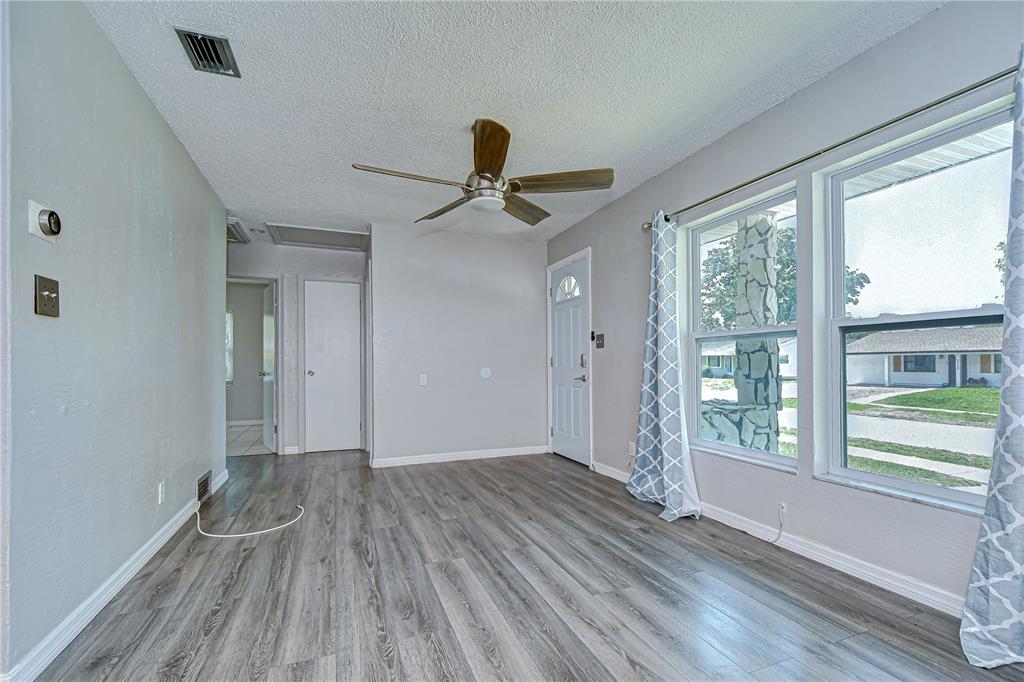 A living room with gray wood-look flooring, a ceiling fan, and a front entry door — 5325 8TH AVENUE S, GULFPORT, FL