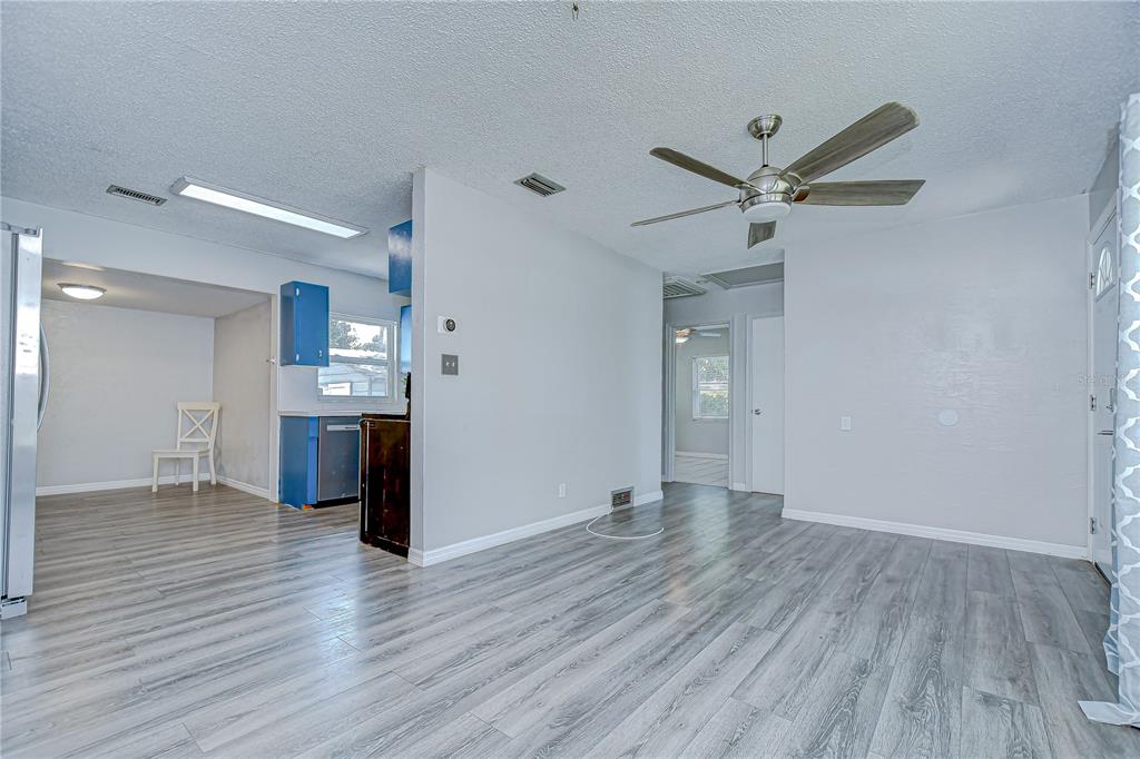 A living room with light wood-look flooring, a ceiling fan, and an adjacent kitchen area — 5325 8TH AVENUE S, GULFPORT, FL