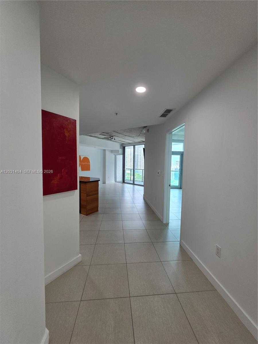 A hallway with light tile flooring leads toward an open living area with floor-to-ceiling windows — 3301 NE 1st Ave # H1206, Miami FL 33137, MIAMI, FL