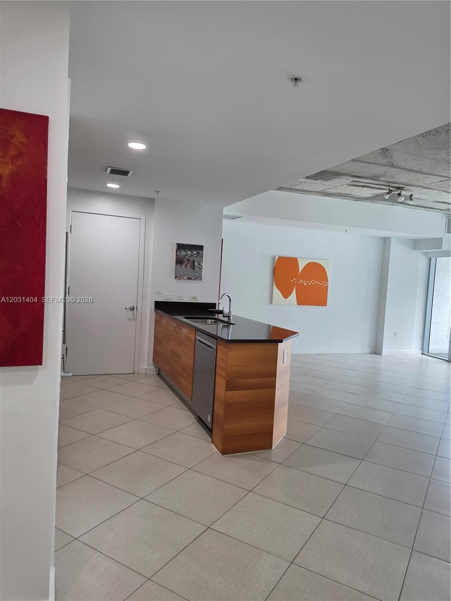A kitchen island with wood cabinetry and a black countertop sits in an open room — 3301 NE 1st Ave # H1206, Miami FL 33137, MIAMI, FL