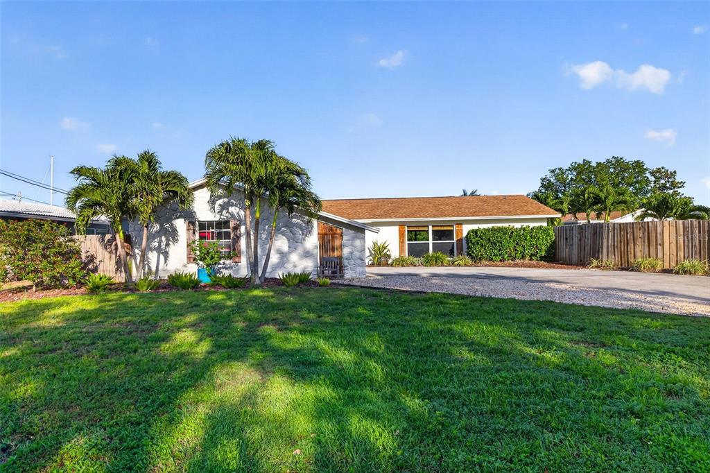 A single-story house with a white stone facade, palm trees, and a gravel driveway — 4200 BEACH DRIVE SE, ST PETERSBURG, FL